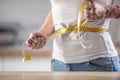 Detail of a woman tightening measuring tape around her waist in an effort to lose weight Royalty Free Stock Photo