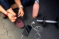 Detail of woman tying footwear to do exercise. Black rubber floor mat and tiles inside a gym. Technology sport with smart phone Royalty Free Stock Photo