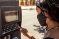 Detail of a woman wearing a protective facial mask using a parking machine in the street. Coronavirus protection in the new normal Royalty Free Stock Photo