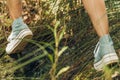 Detail of a woman's feet jumping over wet rocks in a field