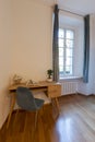 Detail of a wooden desk and an elegant blue chair and a bright window on the right. Ideal location for smartworking Royalty Free Stock Photo