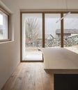 Detail of wooden table with design lamp and window to the forest of the Swiss Alps. Nobody inside