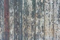 Detail of a wooden wall of a barn made of vertical, weathered boards with peeling green and red paint