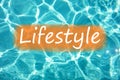 Detail of word `Lifestyle` on swimming pool water and sun reflecting on the surface Royalty Free Stock Photo