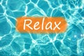 Detail of word & x22;Relax& x22; on swimming pool water and sun reflecting on the surface