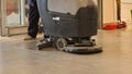 Worker cleaning store floor with machine. Royalty Free Stock Photo