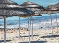 Detail of woven umbrellas above rows on beach in Cyprus.