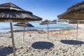 Detail of woven umbrellas above rows of many relaxing beds and l