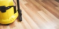 Detail of yellow vacuum cleaner machine on wooden laminated floor - space for text right side Royalty Free Stock Photo