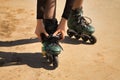 Detail of young girl`s hands fastening and adjusting the zipper of green inline skates