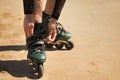 Detail of young girl`s hands fastening the laces of green inline skates