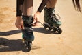 Detail of young girl`s hands fastening the laces of green inline skates in the foreground