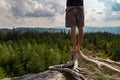 Detail of young man meditating, stretching shoeless on tree stump, Sumava national park, Czech republic