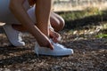 Detail of young sporty girl tying her shoelaces to go for a run in the countryside.concept of sport and healthy life