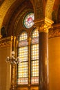 Interior wall and columns with round and arched stained glass windows in Parliament House, Budapest, Hungary; gold leaf trims.