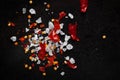 Detailed close-up of Organic red chilli flakes with seed and small crystals of salt, isolated over black background