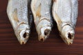 Detailed close up top view shot of three Russian dried salted vobla Caspian Roach fish on a dark wooden plate background