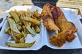 Detailed closeup of british fish and chips in polystyrene takeaway box. Royalty Free Stock Photo