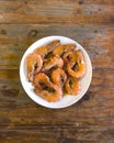 Detailed Closeup of Garlic Shrimps bathed in Chili Sauce, on a white plate on a wood table. A variation of Gambas al Ajillo Royalty Free Stock Photo