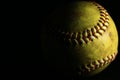 Closeup of a used, yellow softball on a black backround. Royalty Free Stock Photo