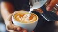 Detailed shot of latte art being crafted, focusing on the barista's skilled hand and the swirling milk creating a