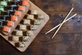 A detailed shot of a set of Japanese sushi rolls and a device for their use chopsticks, which are located on a wooden cutting b Royalty Free Stock Photo