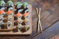 A detailed shot of a set of Japanese sushi rolls and a device for their use chopsticks, which are located on a wooden cutting b Royalty Free Stock Photo