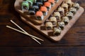 A detailed shot of a set of Japanese sushi rolls and a device for their use chopsticks, which are located on a wooden cutting b Royalty Free Stock Photo