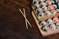 A detailed shot of a set of Japanese sushi rolls and a device for their use chopsticks, which are located on a wooden cutting b Royalty Free Stock Photo