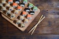 A detailed shot of a set of Japanese sushi rolls and a device for their use chopsticks, which are located on a wooden cutting b Royalty Free Stock Photo