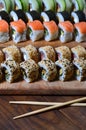 A detailed shot of a set of Japanese sushi rolls and a device for their use chopsticks, which are located on a wooden cutting b Royalty Free Stock Photo