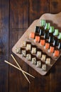 A detailed shot of a set of Japanese sushi rolls and a device for their use chopsticks, which are located on a wooden cutting b Royalty Free Stock Photo