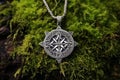 a detailed shot of a silver celtic knotwork amulet on green moss