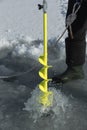 Detailed vertical image of ice auger drill drilling a hole in a frozen dam