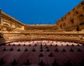 Detailed view from below of the ornaments on the main red wooden door with wrought iron motifs and the cornice with gargoyles of