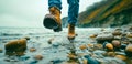 Detailed view of boots walking through water, pebbles splashing Royalty Free Stock Photo