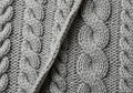 Detailed view of a grey knitted fabric featuring a cable knit pattern. The texture highlights the Royalty Free Stock Photo
