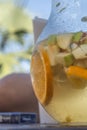 Detailed view at the jar with sliced orange, apple, and cucumber, on champagne sangria drink