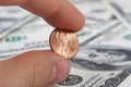 Detailed view of male hand holding a penny on background with money american hundred dollar bills