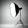 A professional studio lighting setup with a large octagonal softbox on a stand, creating soft diffused light against a grey Royalty Free Stock Photo