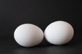 Detailed view profile of two fresh chicken eggs. Isolated on dark background, selective focus. Royalty Free Stock Photo