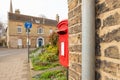 Detailed view of a red Royal Mail box box seen located next to the exterior of a wall belonging to a town house Royalty Free Stock Photo