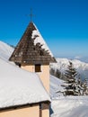 Detailed view of rural mountain church tower with cross on the top in snowy winter alpine landscape Royalty Free Stock Photo