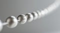 A detailed view of a series of small silver beads arranged in a line along a thin wire. Each bead has a unique shape and