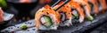 A detailed view of sushi rolls placed on a plate with chopsticks ready to be eaten Royalty Free Stock Photo