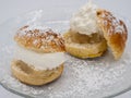 Detailed view of traditional Swedish semla, or fastlagsbulle, with whipped cream, almond paste and confectioners\' sugar.