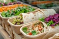 A detailed view of a tray filled with appetizing food items placed on a table, Variety of vegan wraps in compostable containers,
