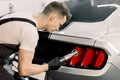Detailing and polishing of car tail light on car. Young professional concentrated Caucasian male worker with orbital Royalty Free Stock Photo