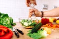 Details of adding salt and pepper to salad. handsome man preparing salad for healthy life