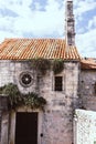 Details of an ancient building in the old town of Budva. Montenegro. Stone church with grass. round stained glass window covered Royalty Free Stock Photo